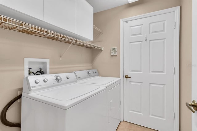 washroom with cabinet space, light tile patterned floors, and washer and clothes dryer