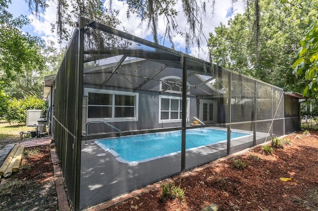 outdoor pool featuring glass enclosure, french doors, and a patio area