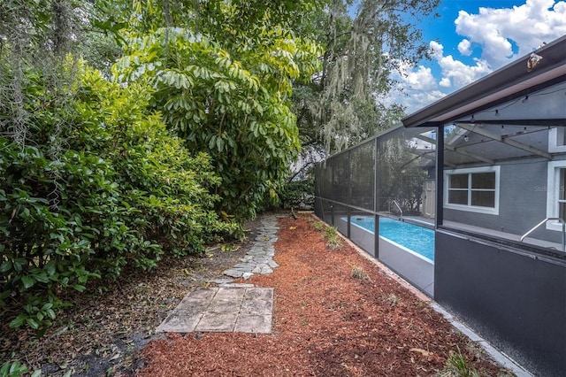 view of yard featuring glass enclosure and an outdoor pool