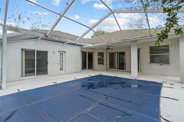 rear view of property with ceiling fan, a lanai, a patio, and a covered pool