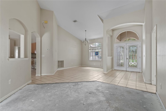 foyer entrance featuring french doors, high vaulted ceiling, and a notable chandelier