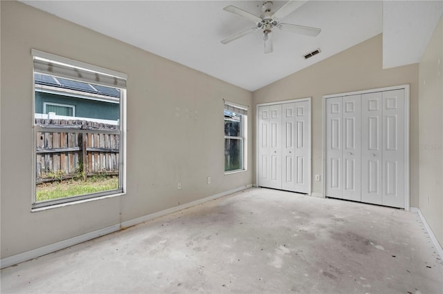 unfurnished bedroom featuring ceiling fan, multiple closets, and vaulted ceiling