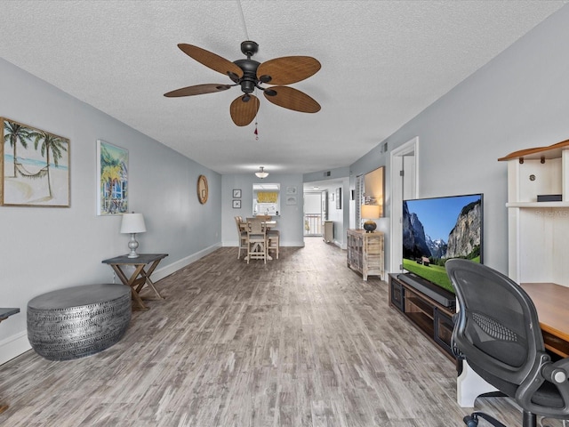 interior space with light wood-type flooring, a textured ceiling, and ceiling fan