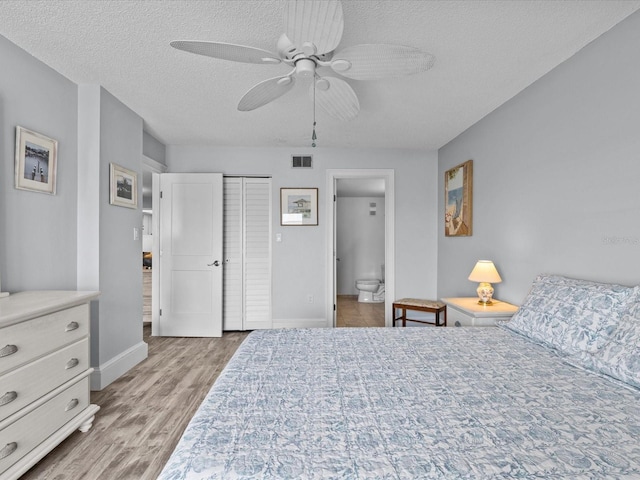 bedroom with a textured ceiling, a closet, connected bathroom, ceiling fan, and light wood-type flooring