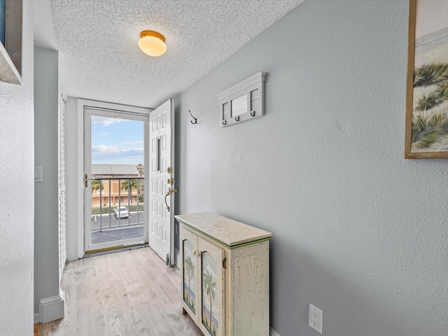 doorway with a textured ceiling and light hardwood / wood-style floors