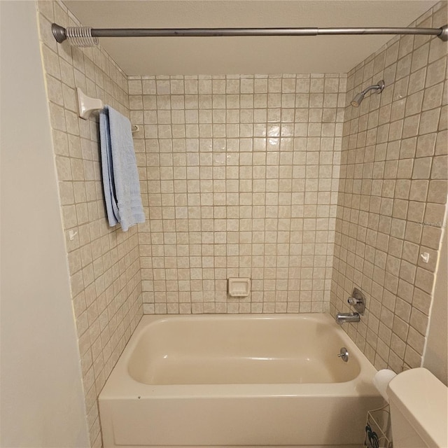 bathroom featuring tiled shower / bath and toilet