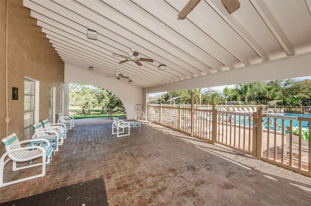 view of patio with a community pool, fence, and a ceiling fan