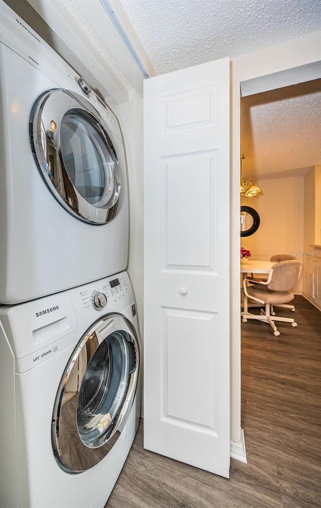 clothes washing area with stacked washer and dryer, wood-type flooring, and a textured ceiling