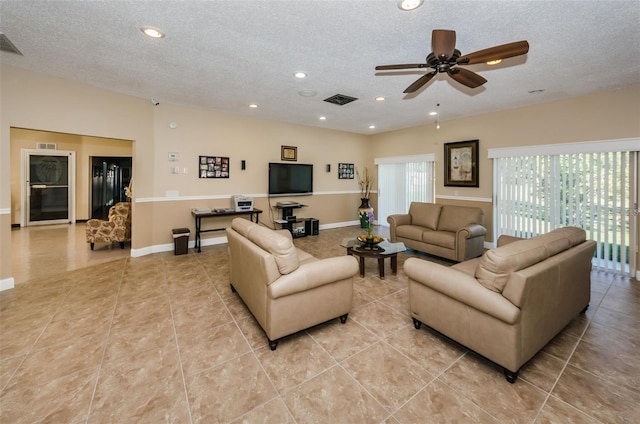 living room featuring ceiling fan, light tile patterned floors, and a textured ceiling