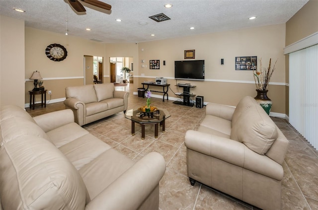 living room featuring ceiling fan, light tile patterned floors, and a textured ceiling