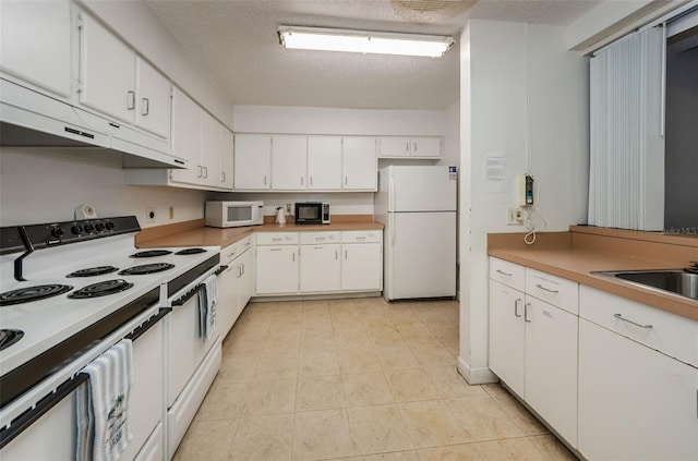 kitchen with sink, light tile patterned flooring, a textured ceiling, white appliances, and white cabinets