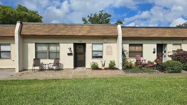 back of house with stucco siding, a patio, and a yard