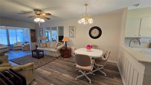 interior space featuring ceiling fan with notable chandelier, a textured ceiling, dark wood-type flooring, and sink