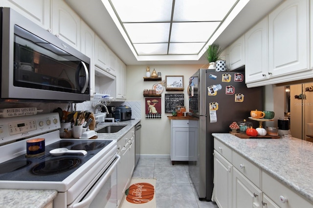 kitchen featuring appliances with stainless steel finishes, white cabinetry, sink, and light tile patterned floors