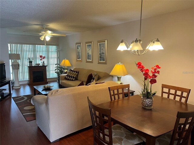 dining area with ceiling fan with notable chandelier, dark hardwood / wood-style flooring, and a textured ceiling