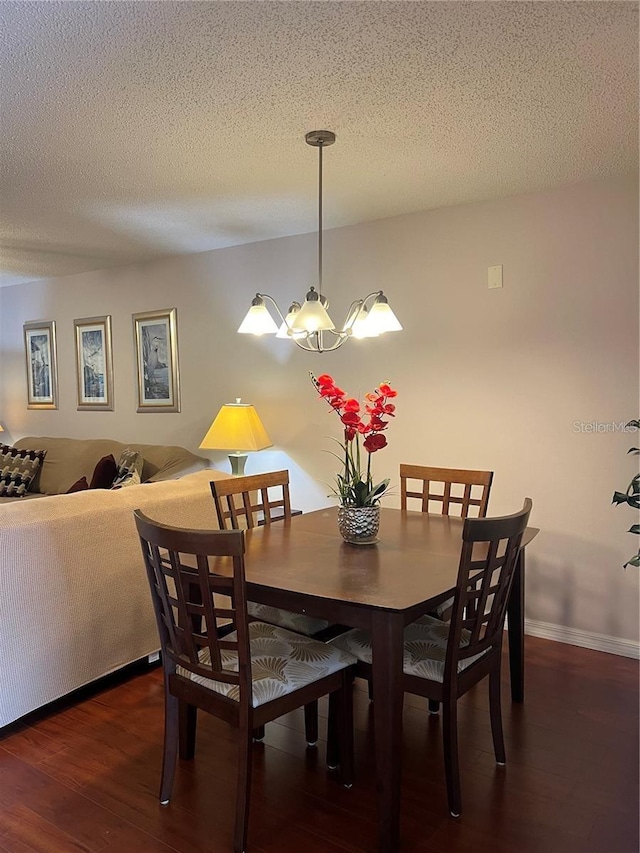 dining space featuring a textured ceiling, a notable chandelier, and dark hardwood / wood-style floors