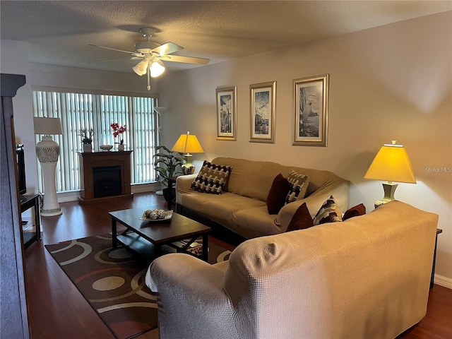 living room with ceiling fan, dark hardwood / wood-style floors, and a textured ceiling