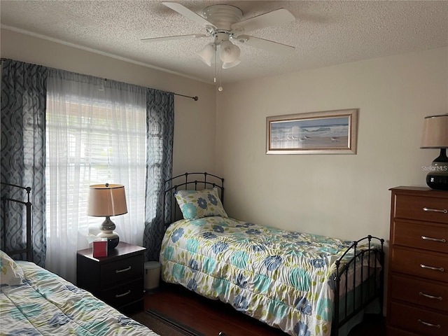 bedroom with a textured ceiling, ceiling fan, and dark hardwood / wood-style floors