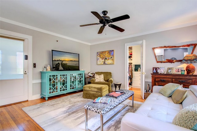 living room featuring hardwood / wood-style floors, ceiling fan, and crown molding