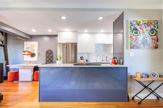 kitchen featuring white cabinetry, gas stovetop, high end fridge, decorative backsplash, and light hardwood / wood-style flooring