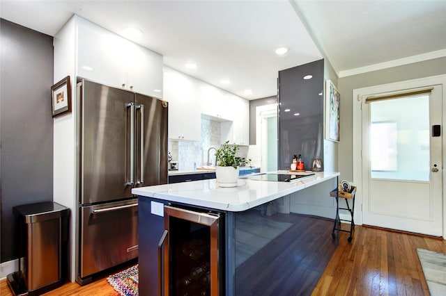 kitchen with wine cooler, high quality fridge, backsplash, white cabinets, and light wood-type flooring