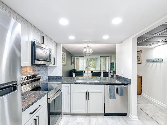 kitchen featuring an inviting chandelier, tasteful backsplash, stainless steel appliances, sink, and dark stone countertops