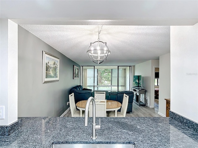 dining room with light wood-type flooring, a notable chandelier, a textured ceiling, and sink