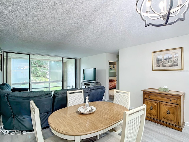 dining room with an inviting chandelier, a textured ceiling, and light hardwood / wood-style flooring