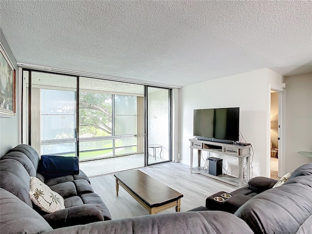 living room featuring light wood-type flooring, a textured ceiling, and expansive windows