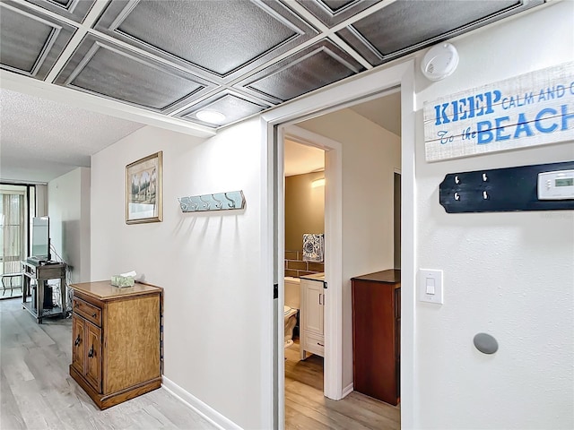 hall featuring light wood-type flooring and coffered ceiling