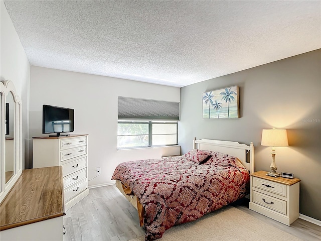 bedroom featuring light hardwood / wood-style floors and a textured ceiling