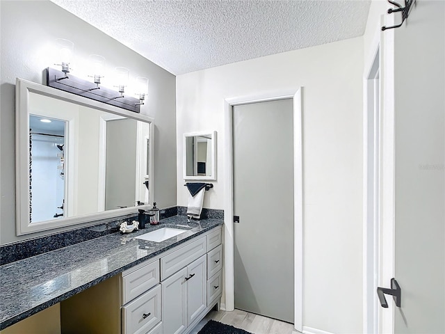 bathroom with a textured ceiling, vanity, and wood-type flooring