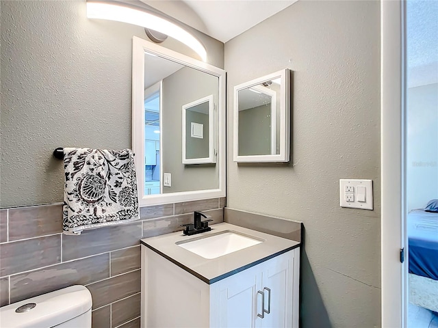 bathroom with vanity, toilet, and backsplash