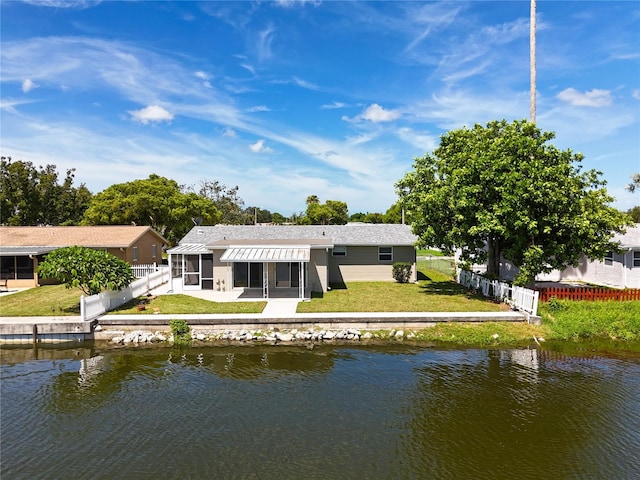 rear view of property with a sunroom, a water view, and a yard