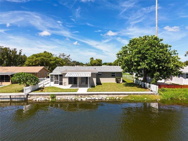 rear view of property featuring a sunroom, a water view, a yard, and a fenced backyard