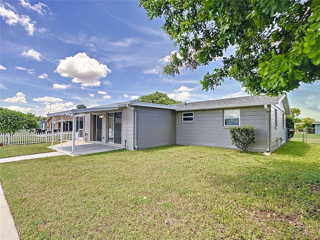 rear view of house with a lawn, a patio area, and fence