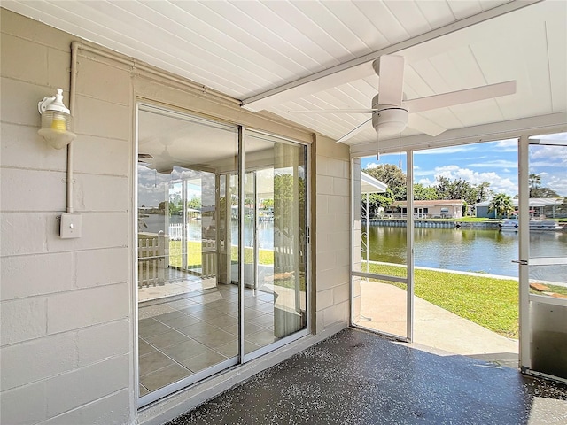 unfurnished sunroom with ceiling fan and a water view