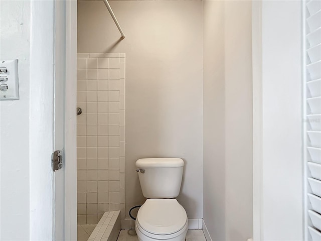 bathroom with a tile shower, tile patterned flooring, and toilet