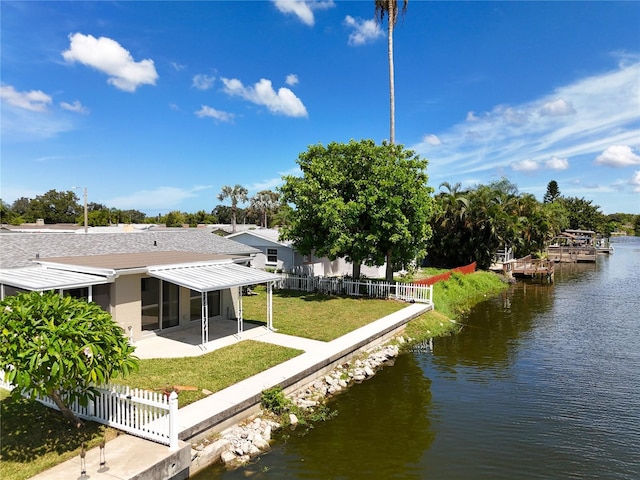 rear view of property with a sunroom, a yard, a water view, and a patio