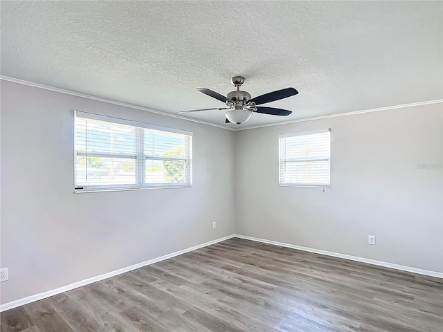 spare room featuring hardwood / wood-style floors, crown molding, and a wealth of natural light