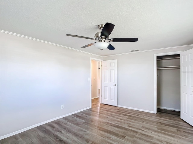 unfurnished bedroom featuring a textured ceiling, a closet, hardwood / wood-style flooring, and ceiling fan