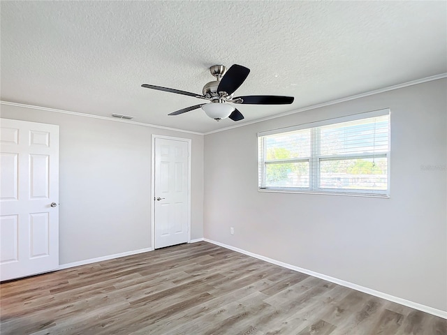 spare room with ceiling fan, ornamental molding, a textured ceiling, and light hardwood / wood-style flooring