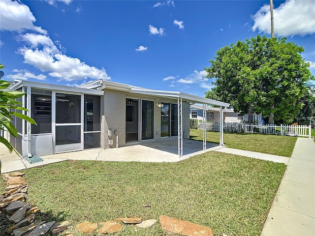 back of property with a lawn, a patio area, and a sunroom