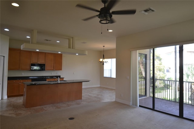 kitchen with ceiling fan with notable chandelier, black appliances, pendant lighting, a kitchen island with sink, and sink