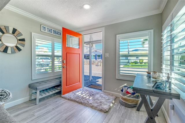 entryway featuring a textured ceiling, wood finished floors, baseboards, and ornamental molding