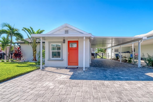 exterior space featuring an attached carport, a yard, and stucco siding