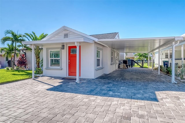 view of front facade featuring stucco siding, a shingled roof, and an attached carport