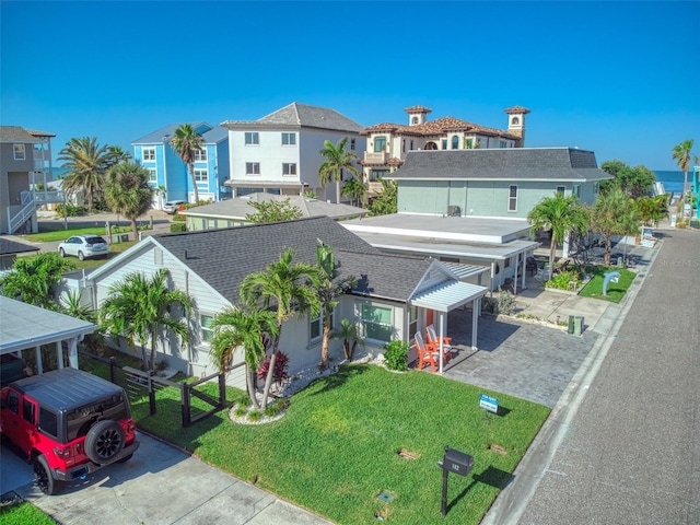 exterior space with a residential view, roof with shingles, a front yard, and fence