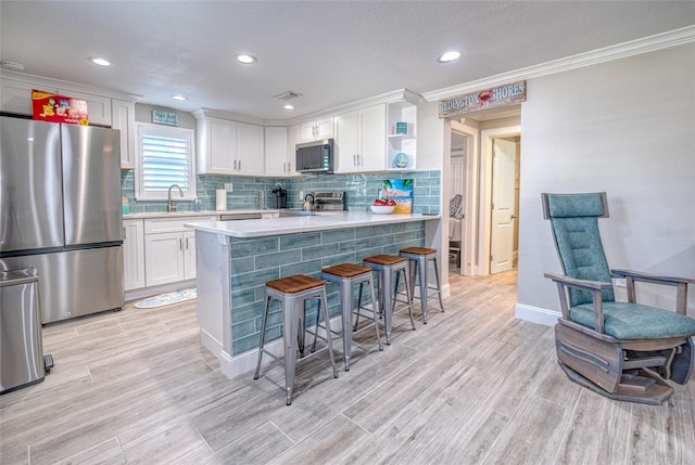 kitchen featuring appliances with stainless steel finishes, white cabinetry, light countertops, and a sink