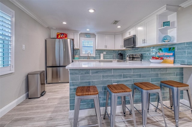 kitchen with visible vents, a sink, white cabinetry, appliances with stainless steel finishes, and a peninsula